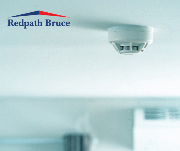 image shows a smoke alarm on a white painted ceiling.